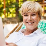 Woman smiling outdoors with computer