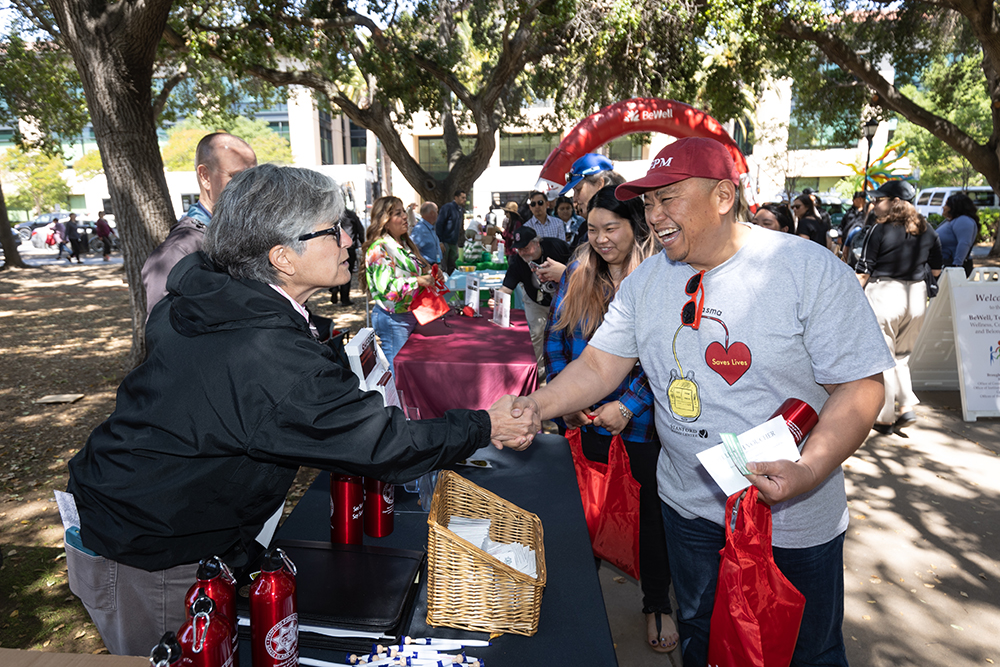 Employee interacts with exhibitor at Stanford campus event