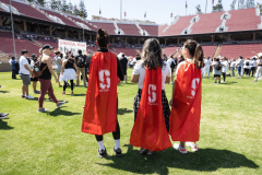 Three people standing with red Stanford superhero capes on