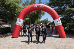 Three people walking through a red BeWell archway